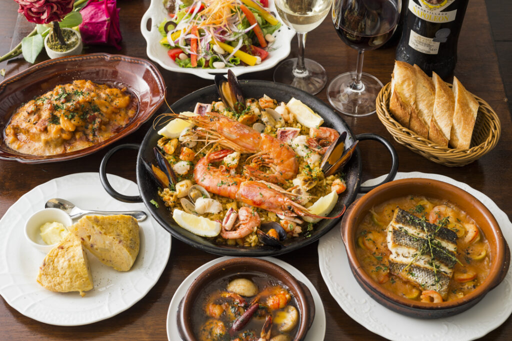 複数皿の写真。スペイン料理のパーティ料理有頭海老のパエリア、アヒージョ、オムレツなど