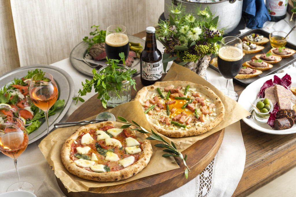 複数皿の写真。イタリア料理のパーティ料理。2枚のピザ、サーモンサラダ、その他の皿。
